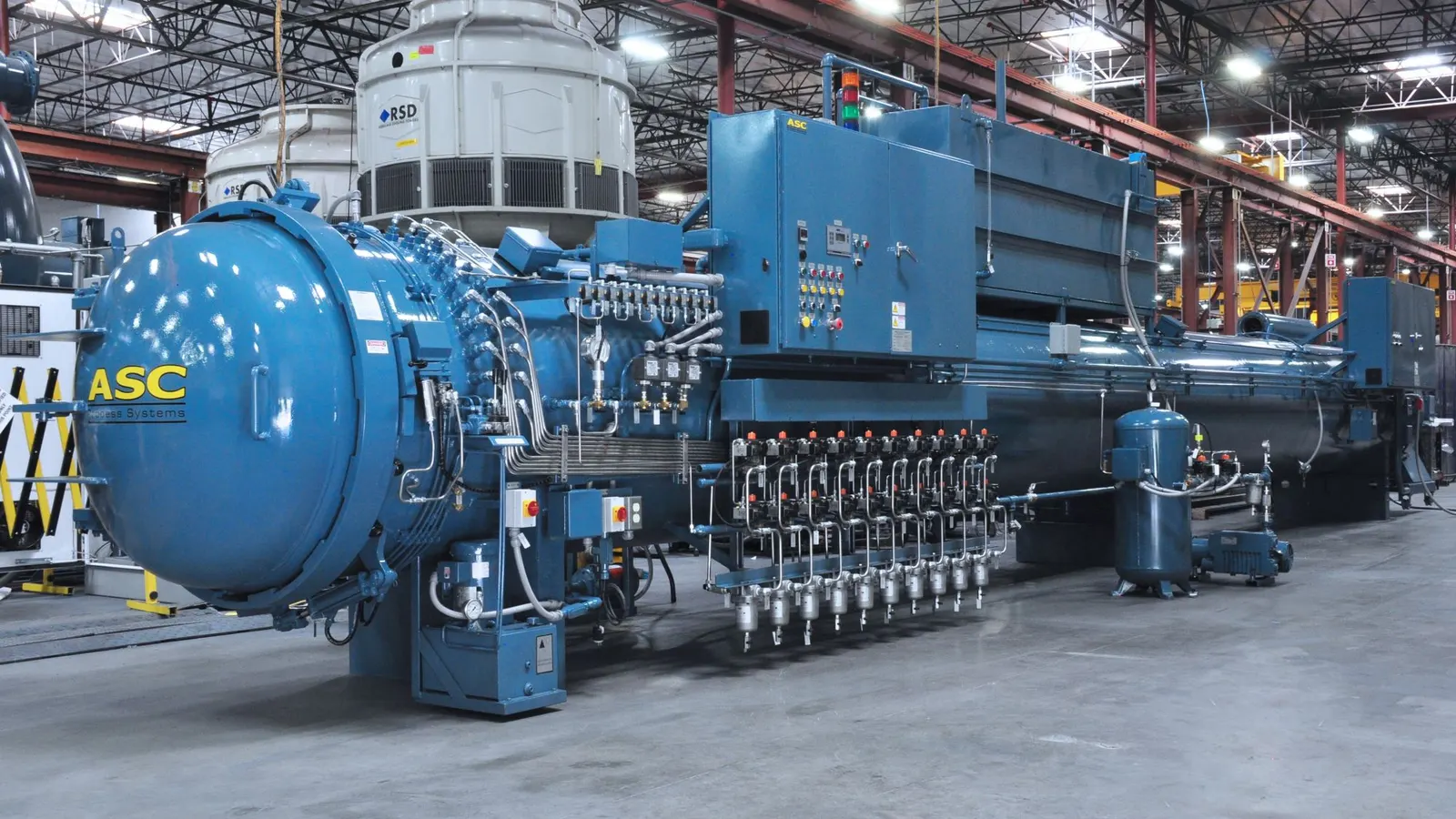A blue Econoclave with its CPC control cabinet, vacuum manifold, and receiver tank on the shop floor