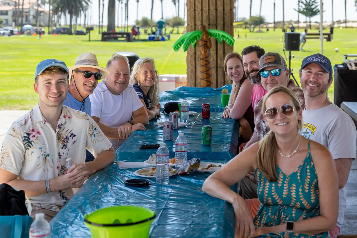 Smiling employees at a long picnic table in the park