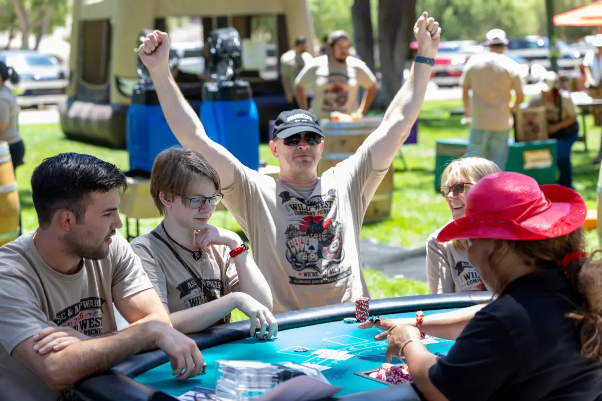 An employee cheering with both arms up at the blackjack table
