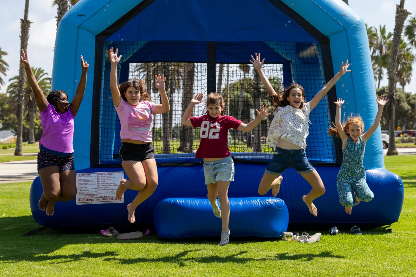 Kids leaping in the air in front of a bounce house