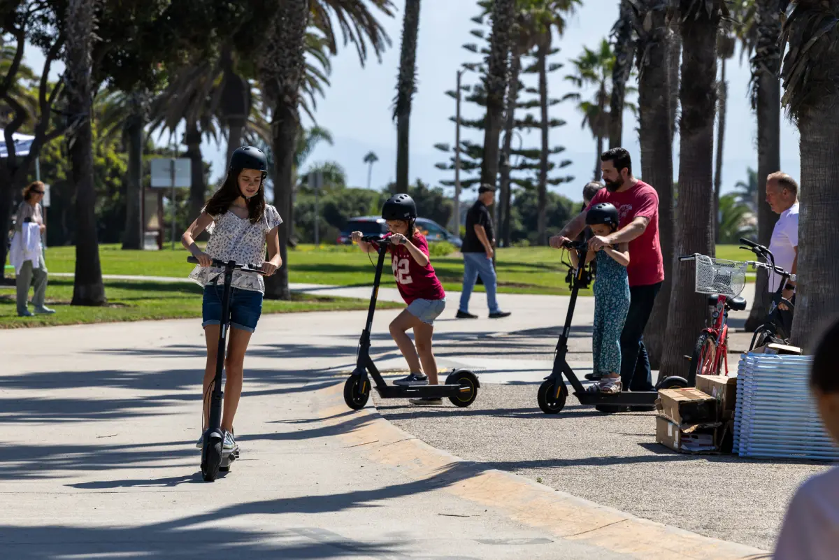 Employees and kids riding scooters along the beach path