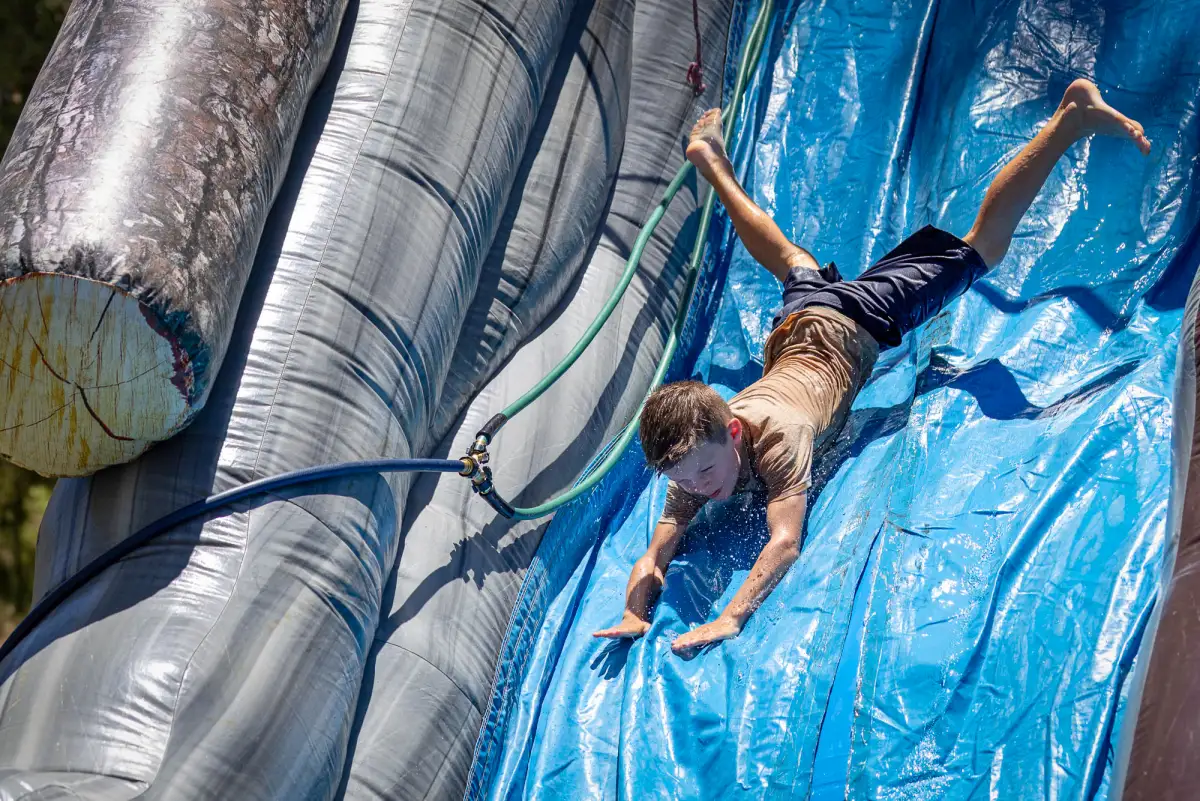 A kid flying head first down an inflatable water slide