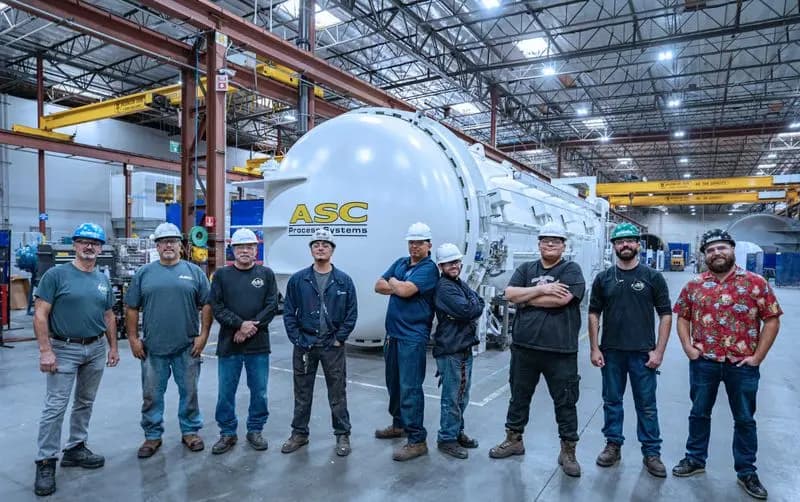An ASC crew lined up in front of a finished autoclave in the shop