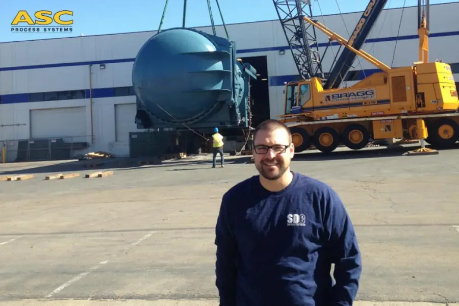 An ASC field engineer on a customer site as a crane sets an autoclave behind him