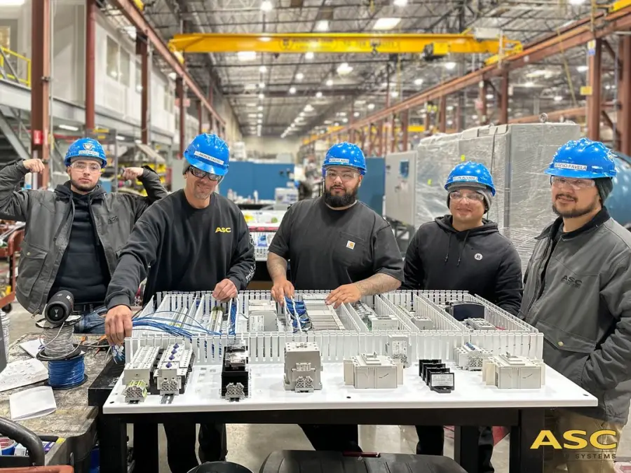 ASC electricians in hard hats with a control panel they built