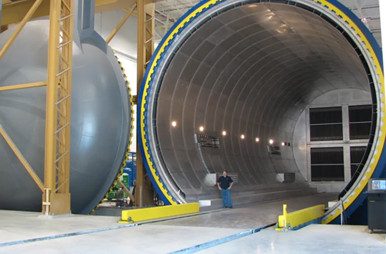 A person standing inside a giant open ASC Econoclave, framed by its yellow locking ring