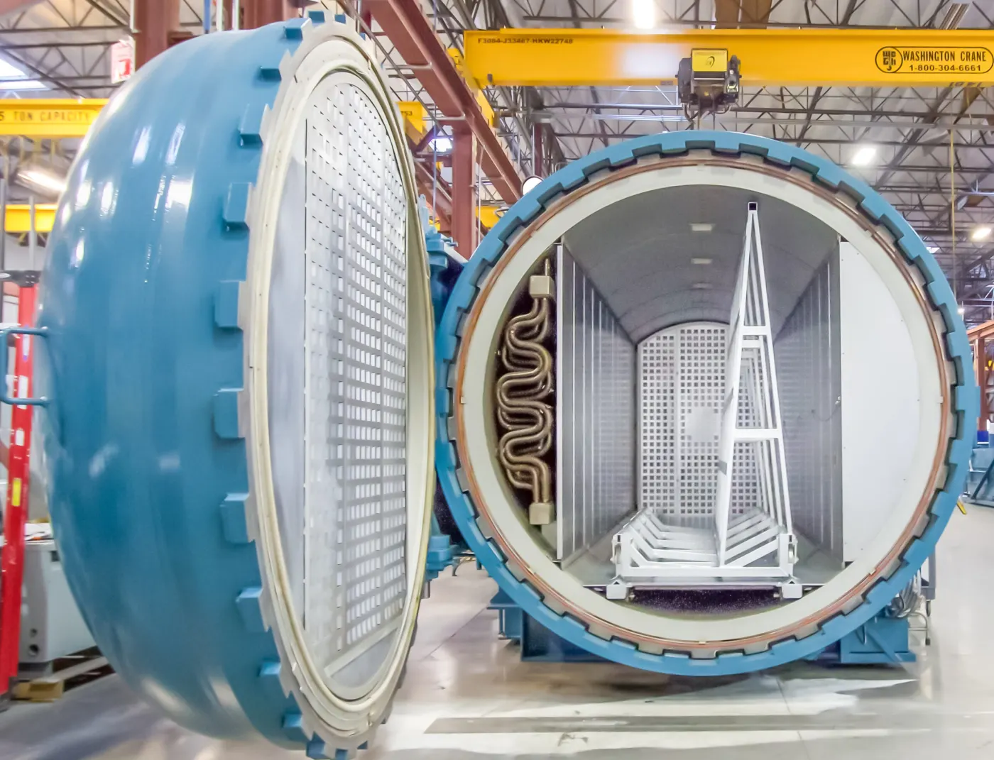 A glass rack on a loading cart in front of an open Econoclave GLS autoclave