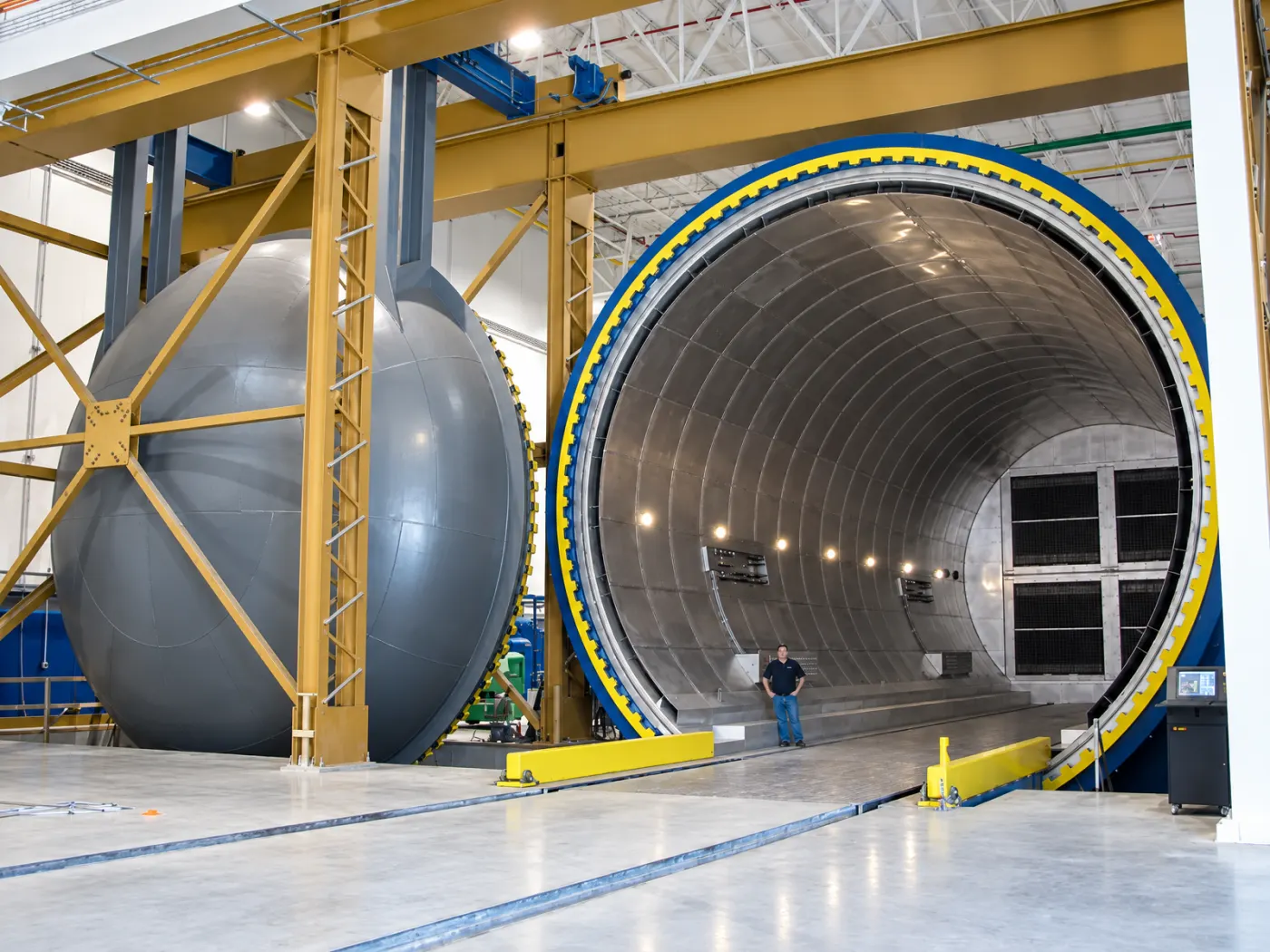 A person standing at the open door of a 30 ft diameter ASC composite autoclave